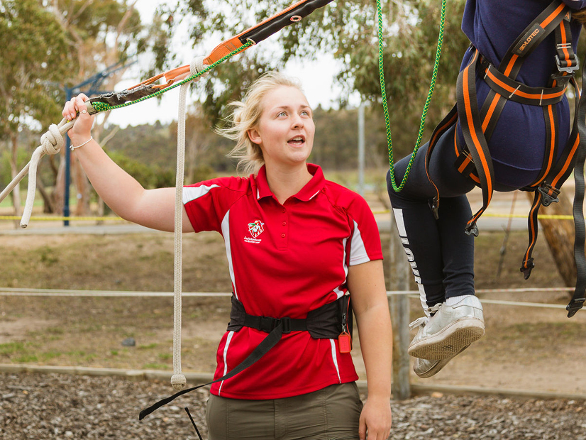Staff member is providing guidance to a participant using the giant swing.