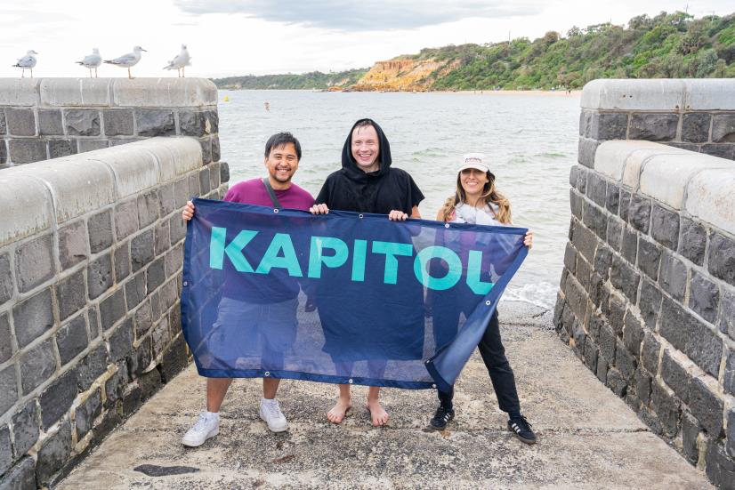 Anton holding a Kapitol-branded flag after a swim