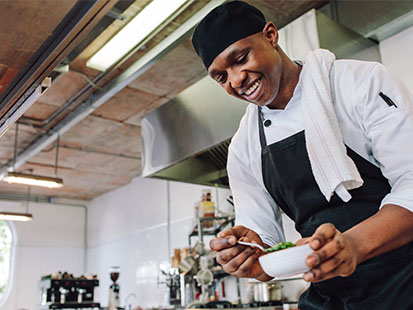 Chef plating up food in kitchen