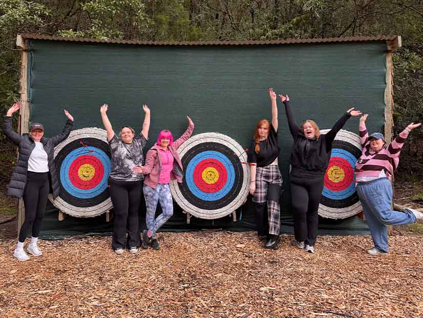 Group of people posing in front of archery targets