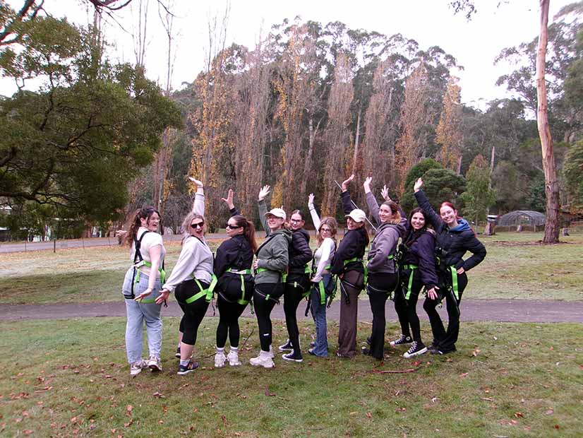 Group posing outdoors wearing safety harness