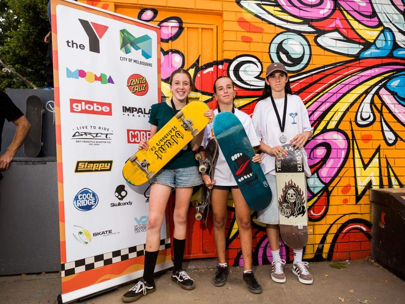3 teenagers stood next to a board displaying the Moomba sponsor's logos
