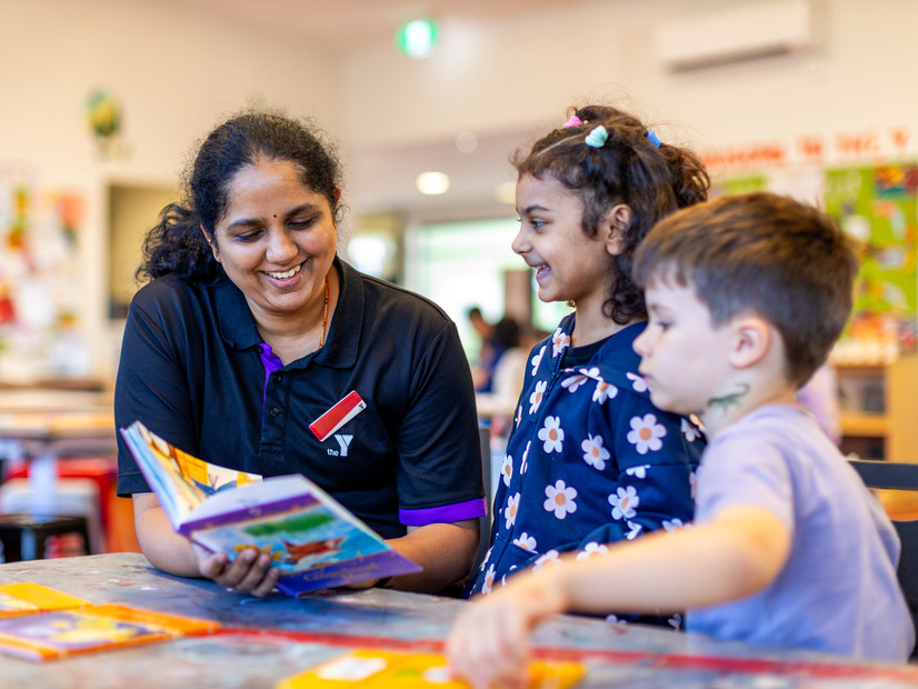 Y Victoria Educator reads a book with two children.